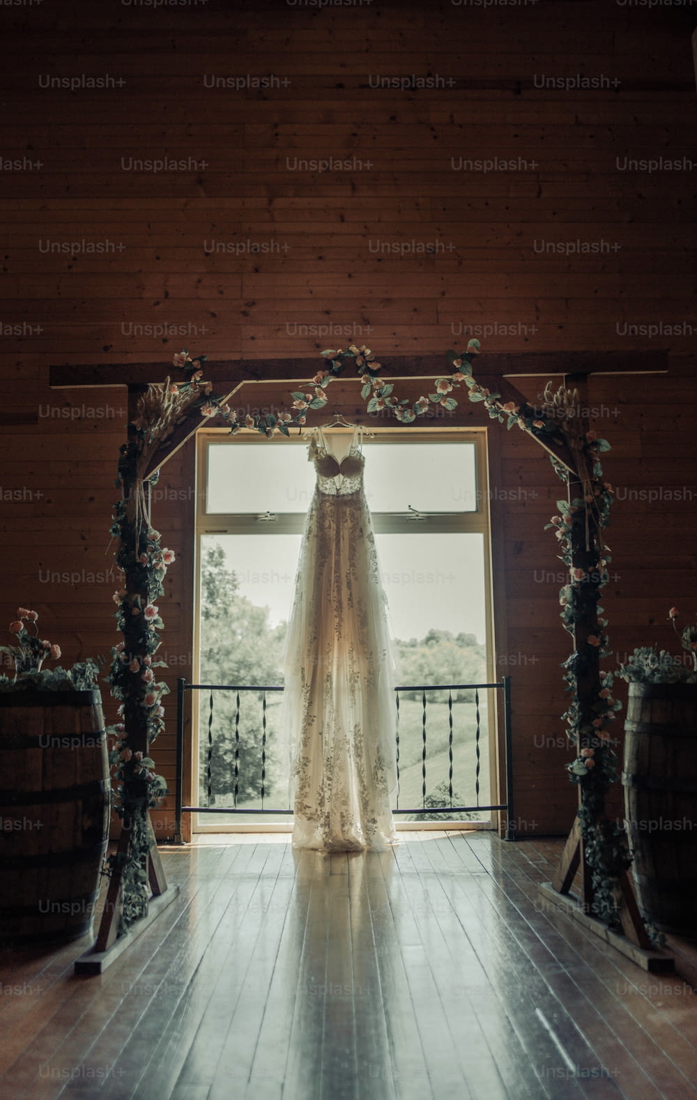 a wedding dress hanging in front of a window