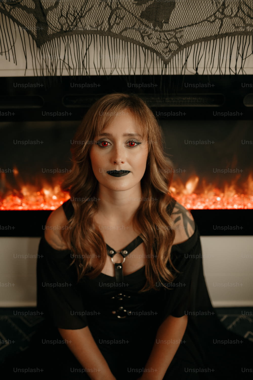 a woman with a fake mustache sitting in front of a fireplace