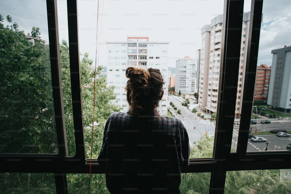 a person looking out a window at a city