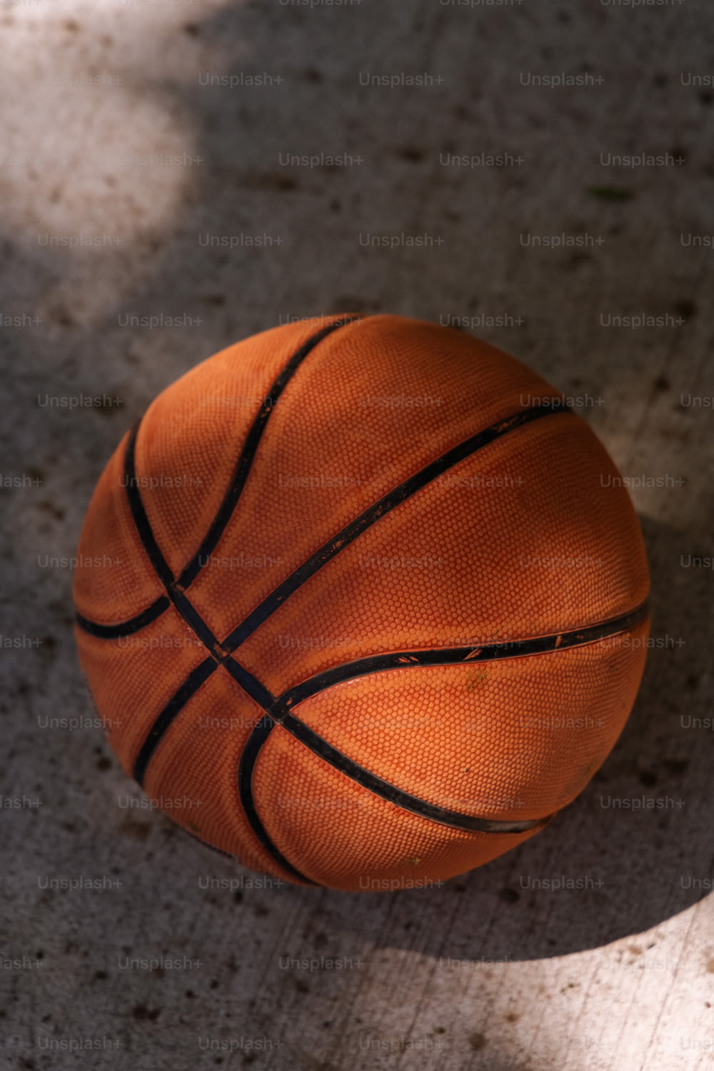 uma bola de basquete sentada no chão à sombra