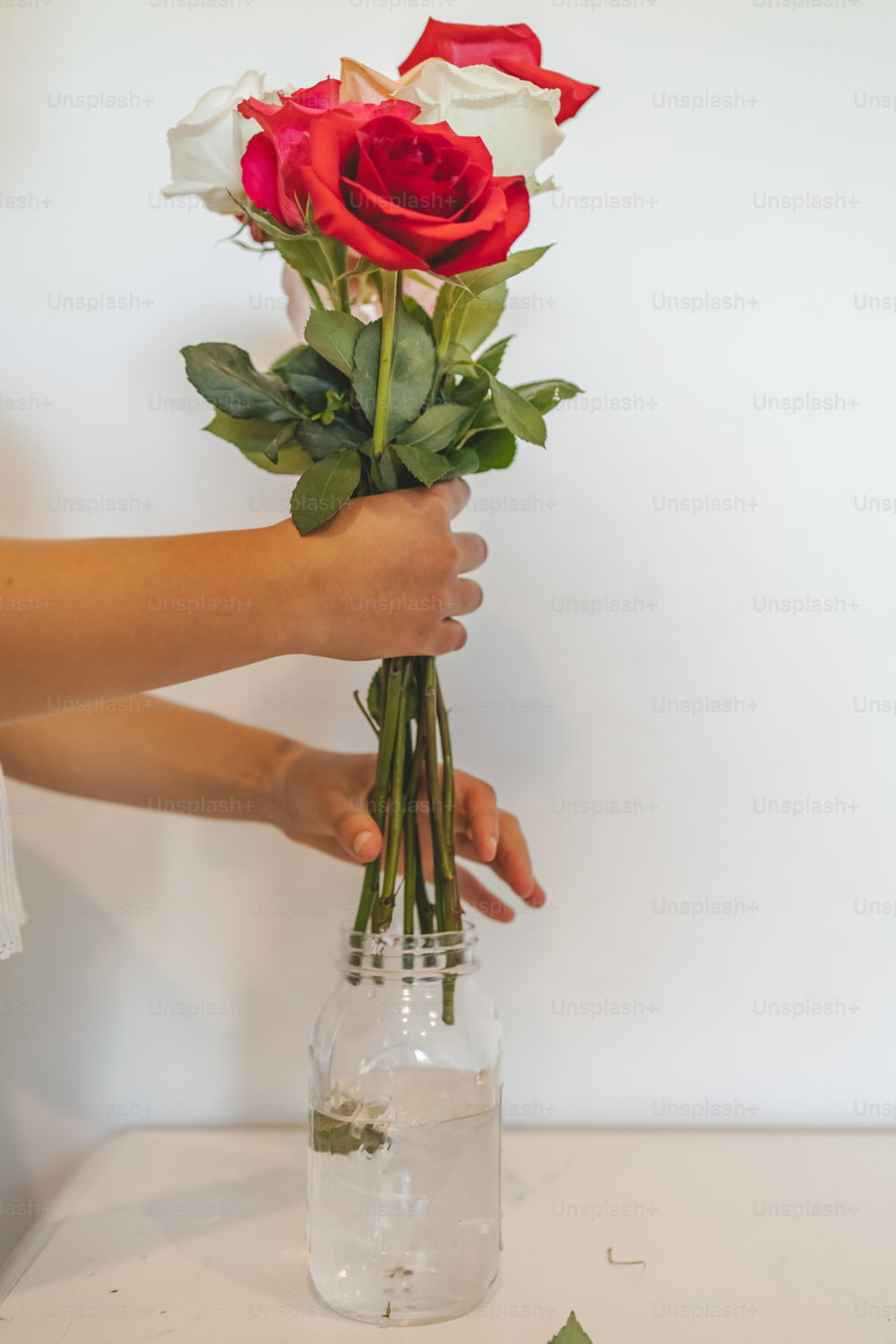 une personne tenant un bouquet de roses dans un vase