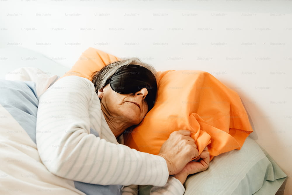 Una mujer acostada en la cama con una almohada naranja