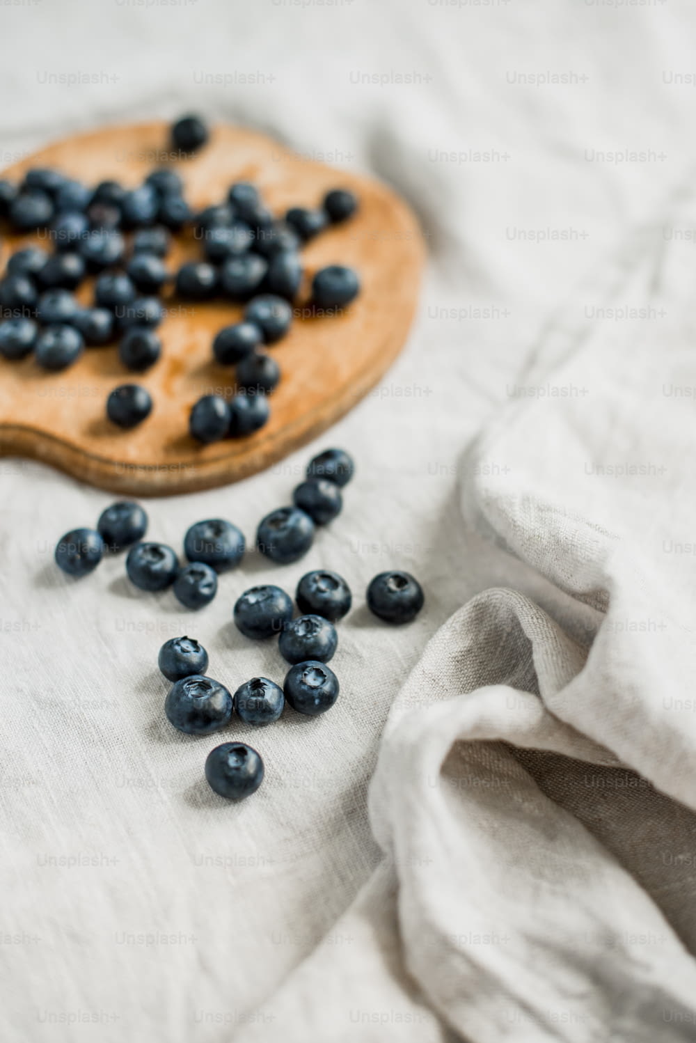 a wooden spoon with blueberries on a white cloth