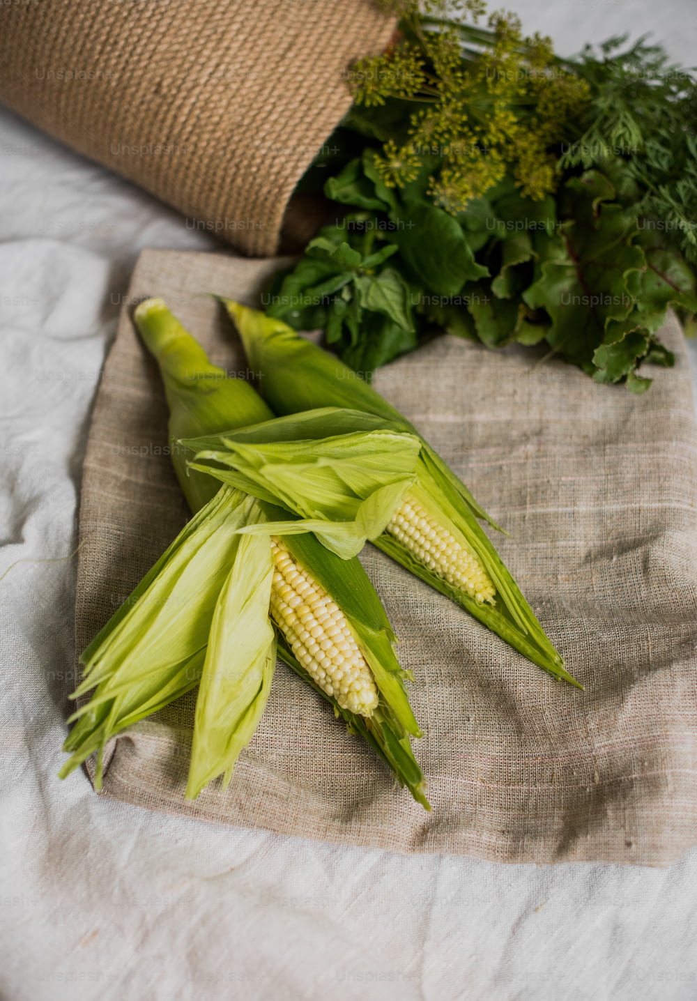 Maiskolben und anderes Gemüse auf einem Tuch
