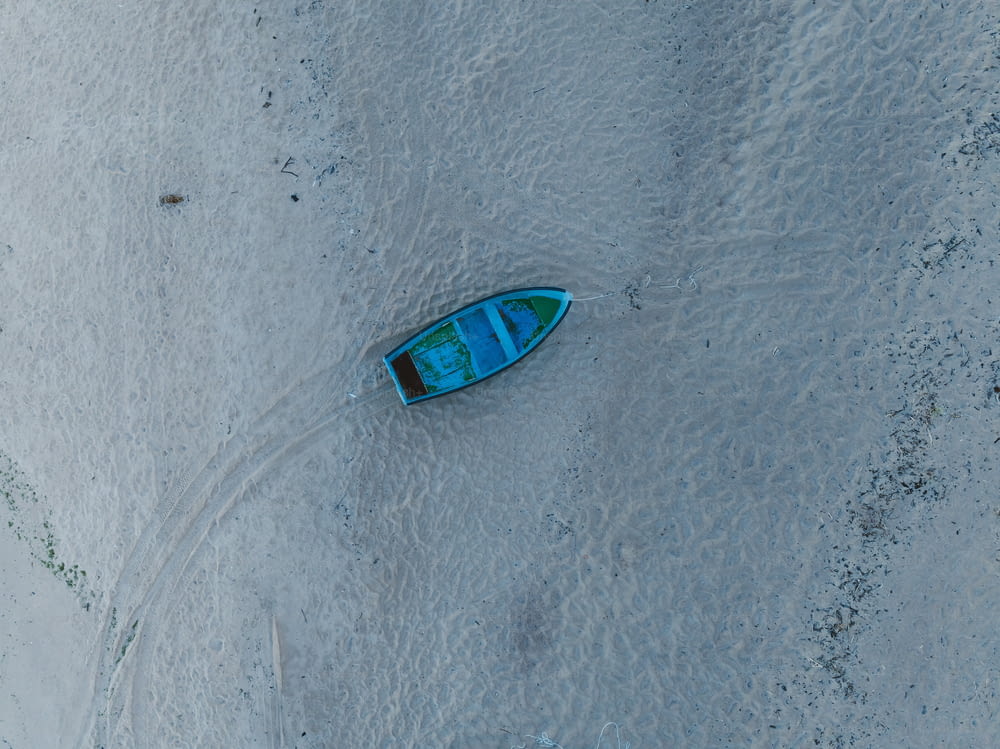 砂浜の上に座っている小さな青いボート