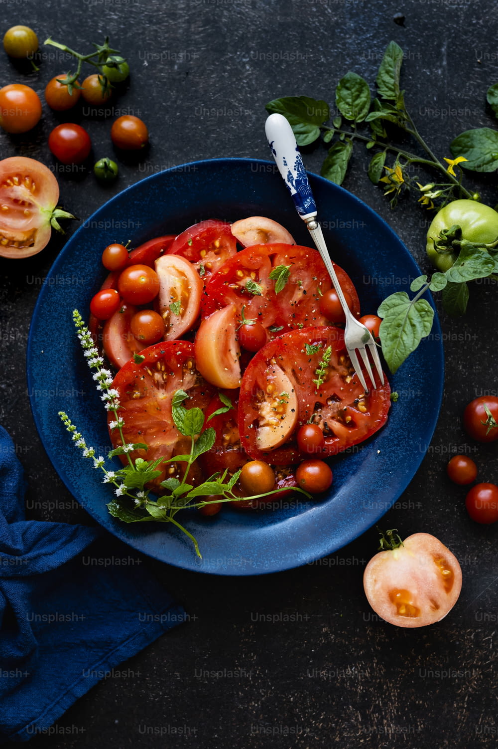 a blue plate topped with sliced tomatoes and a fork