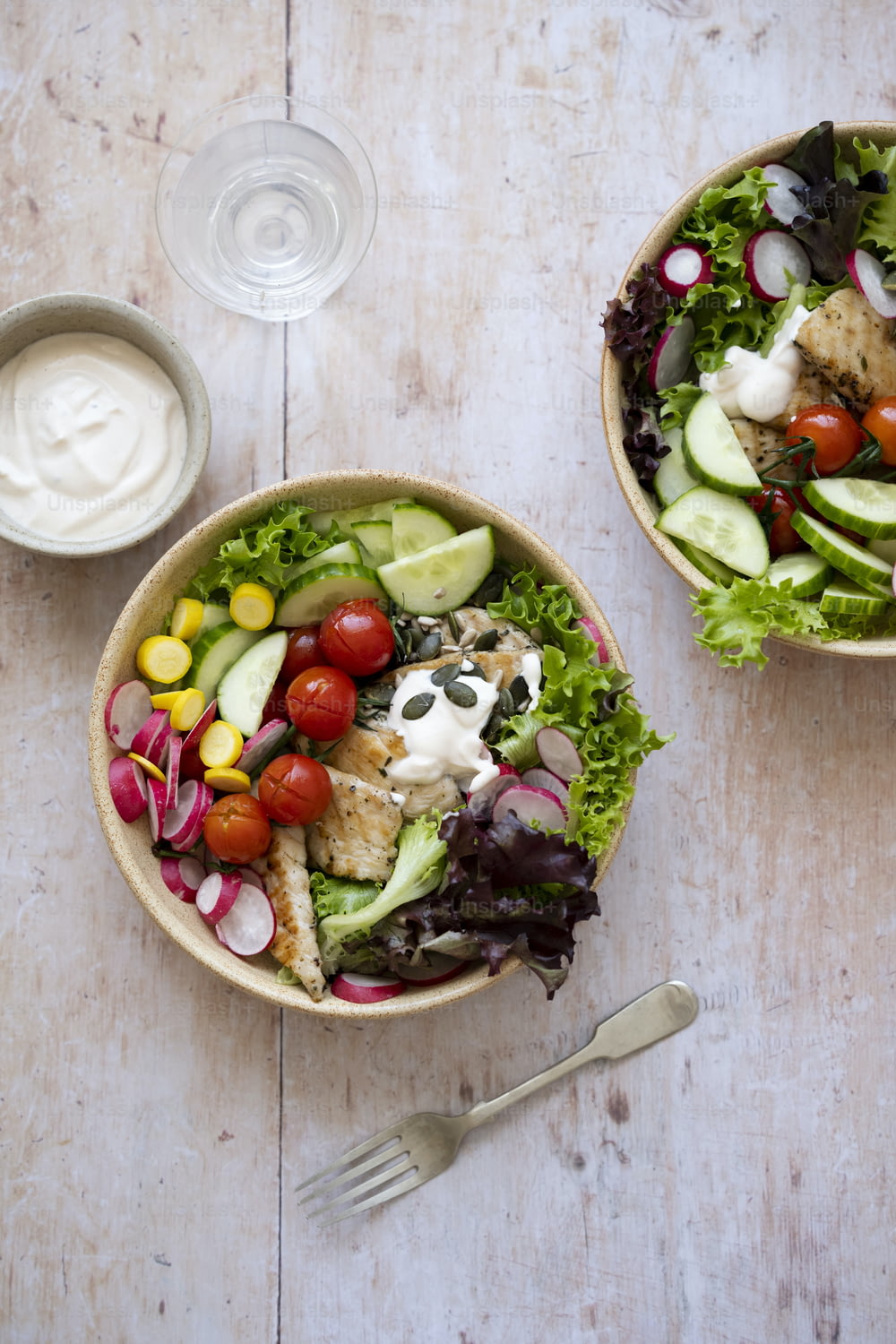 two bowls of salad with dressing on the side