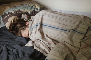 Une jeune fille dormant dans un lit sous une couverture