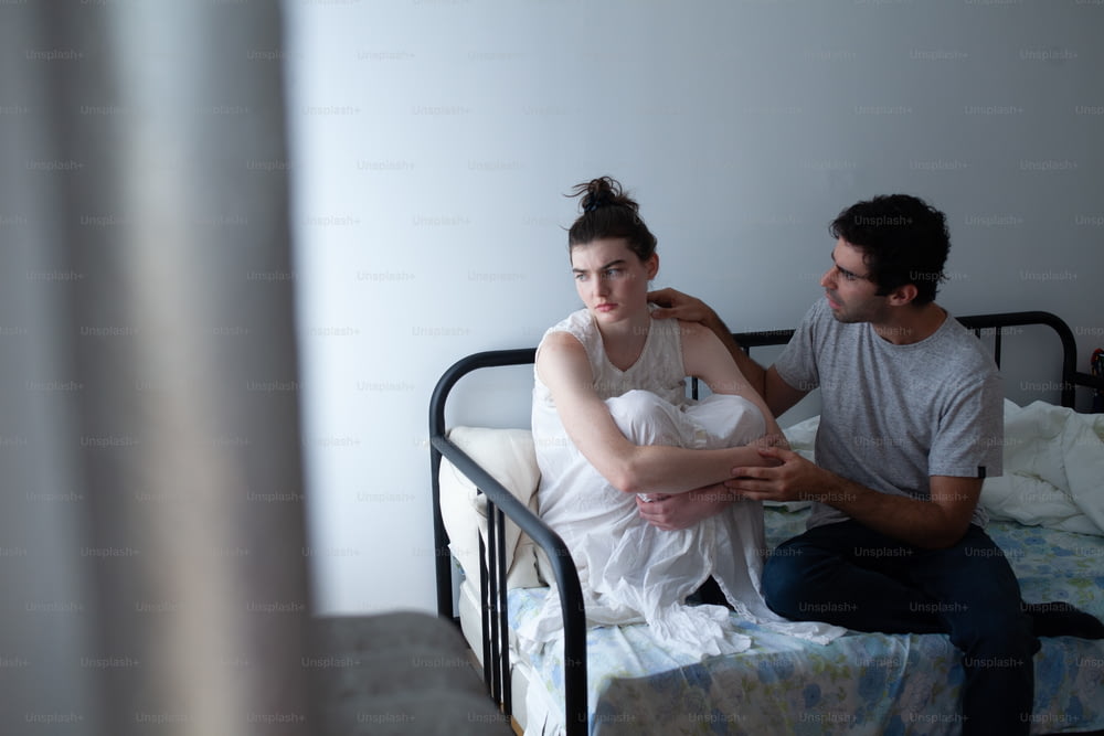 un homme assis à côté d’une femme sur un lit