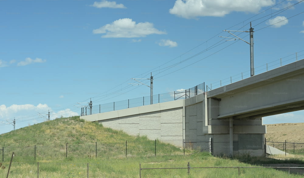 un puente sobre una colina cubierta de hierba con líneas eléctricas sobre ella