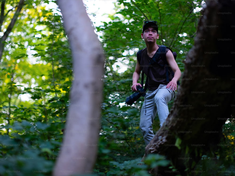 Un uomo in piedi nel bosco con una macchina fotografica