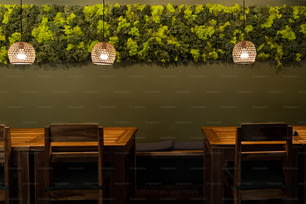 a green wall with three hanging lights above a wooden table