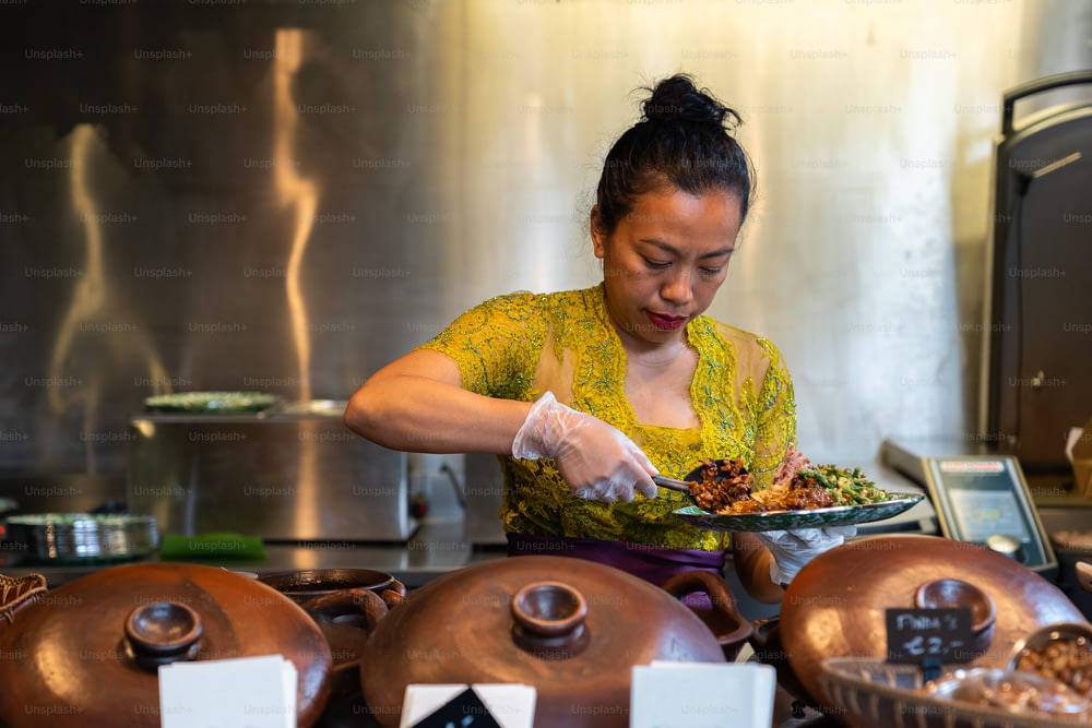 uma mulher em uma cozinha preparando comida em um prato