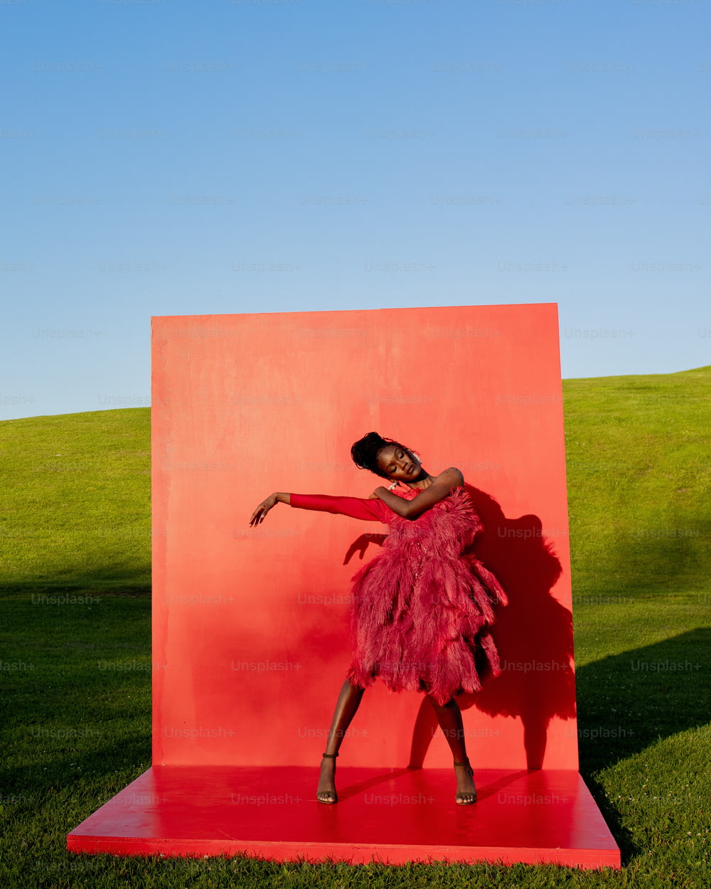 a woman in a pink dress is standing in front of a red sculpture