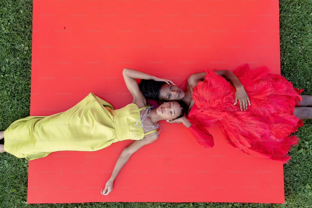 two girls laying on a red mat on the grass