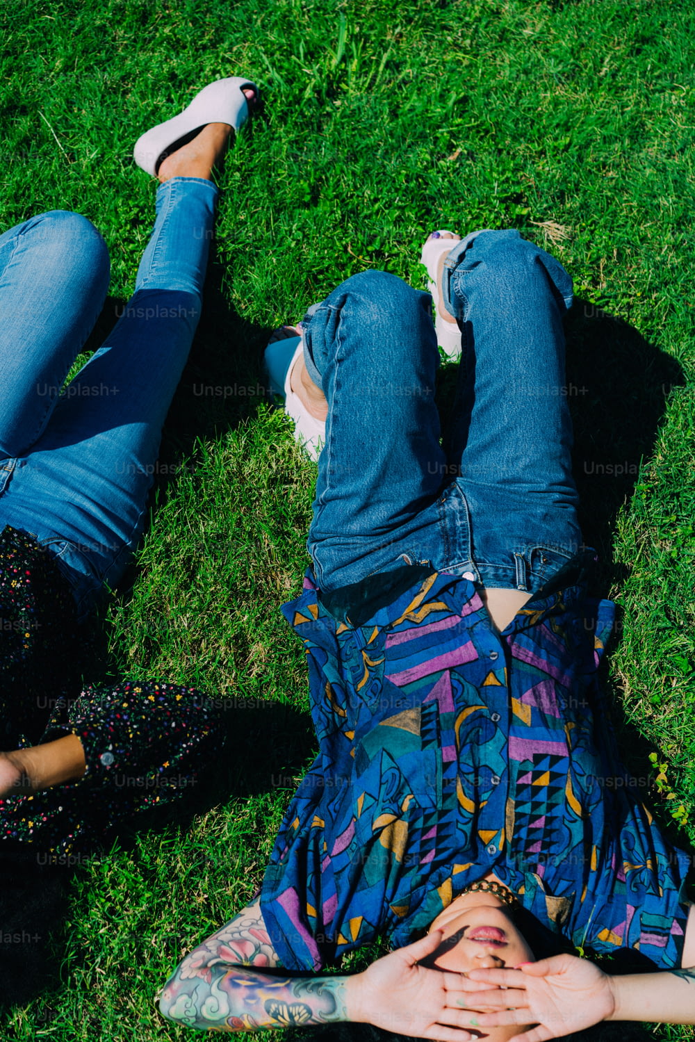 a couple of people laying on top of a lush green field