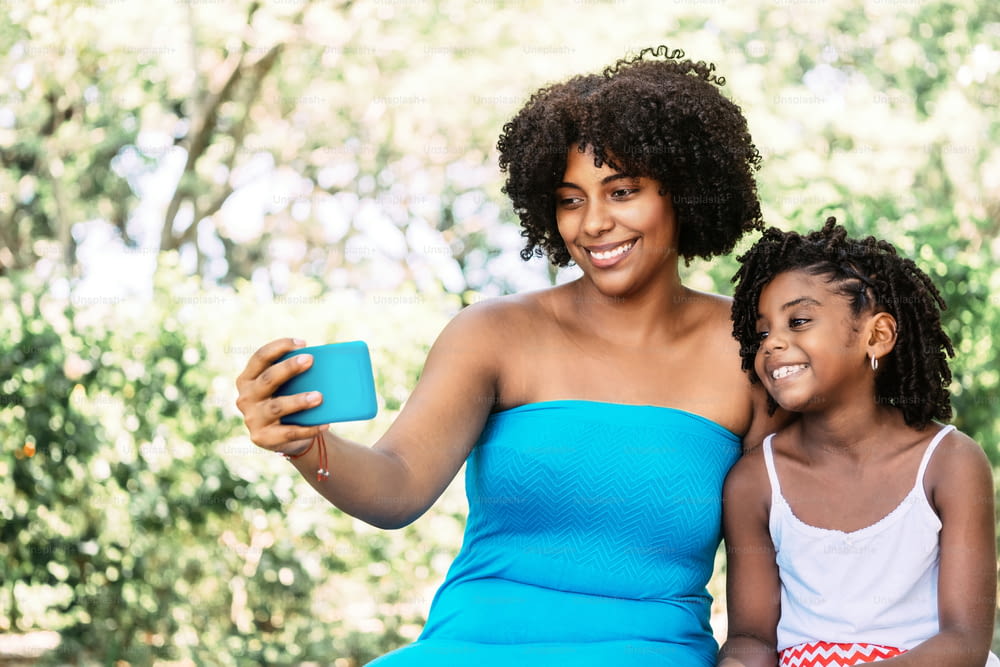 Retrato de una mujer afroamericana con una niña sonriente y alegre tomando una selfie. concepto de tecnología.