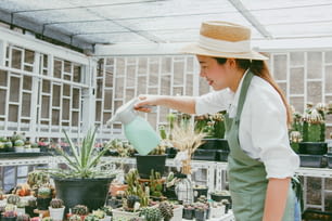 Joven mujer asiática SME pequeña empresa empresaria riega la planta en la granja de cactus
