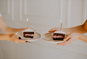 Dos personas sosteniendo platos con dos rebanadas de pastel