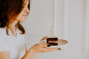 Una mujer sosteniendo un plato con un pedazo de pastel