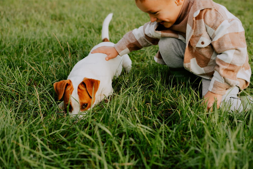 Un ragazzino che gioca con un cane nell'erba