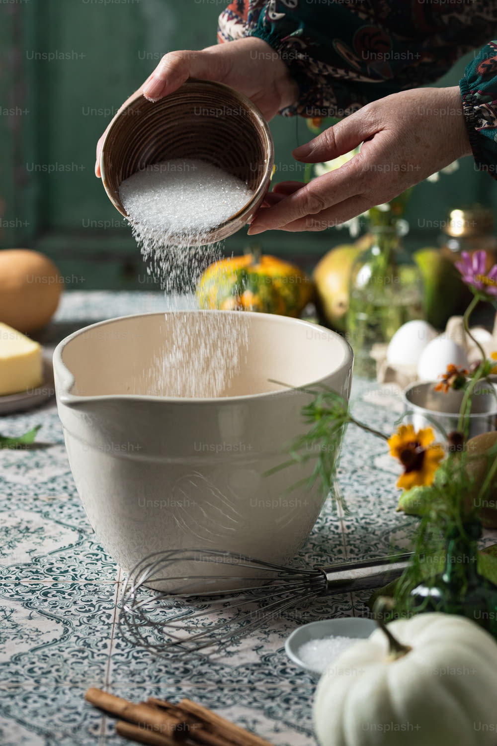 a person pouring sugar into a bowl on a table