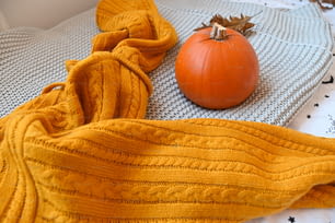 a knitted blanket and a pumpkin on a bed