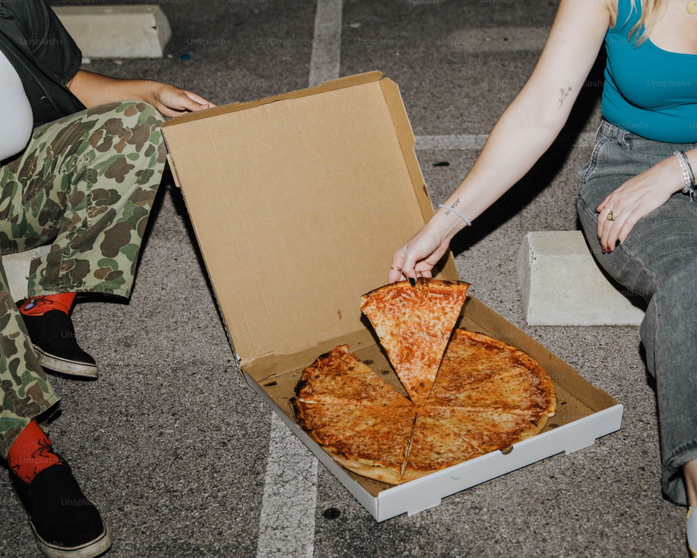 a woman is taking a slice of pizza from a box