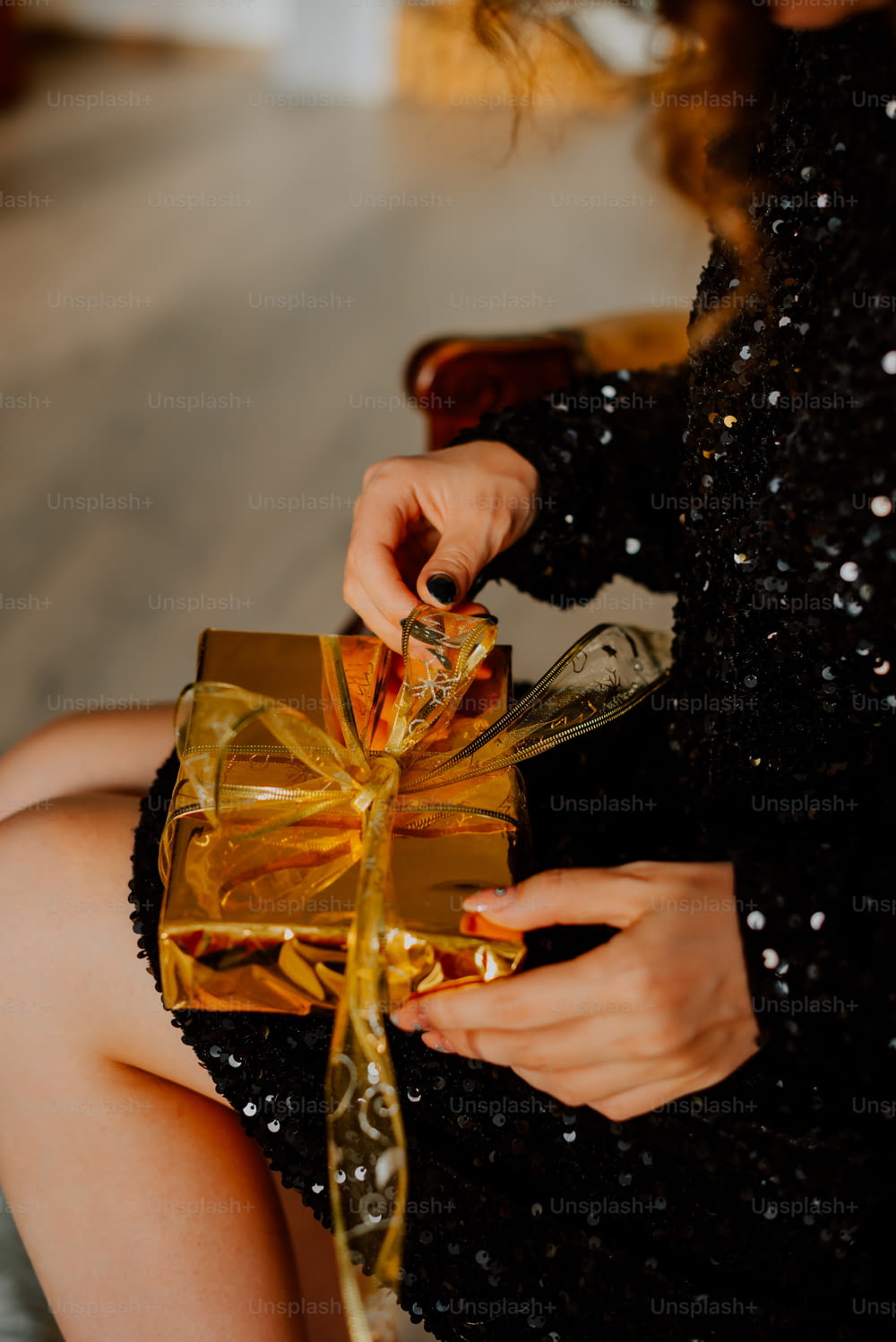 a woman in a black dress holding a gold gift box