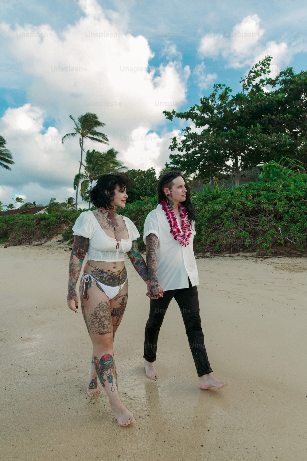 a couple of women walking across a sandy beach