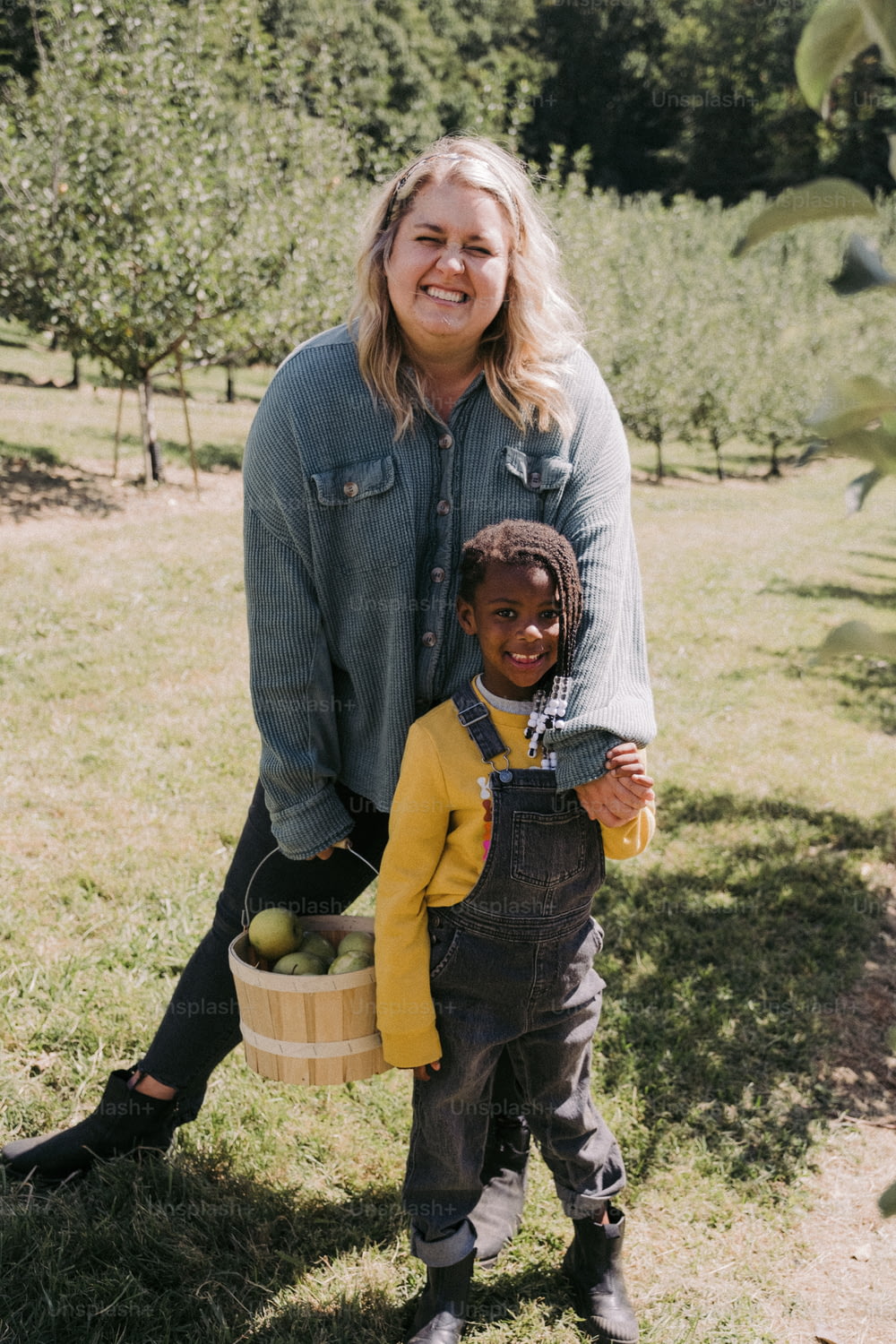 a woman holding a basket of apples next to a child