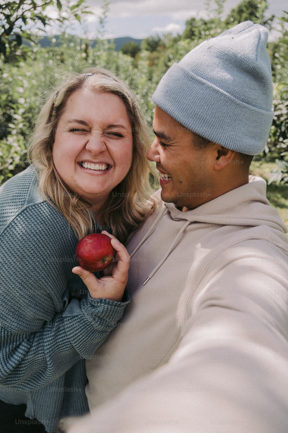 Un homme et une femme sourient en tenant une pomme