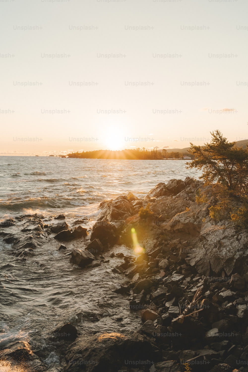 Le soleil se couche sur l’eau et les rochers