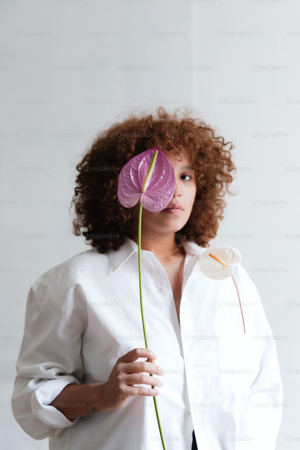 uma mulher com cabelo encaracolado segurando uma flor
