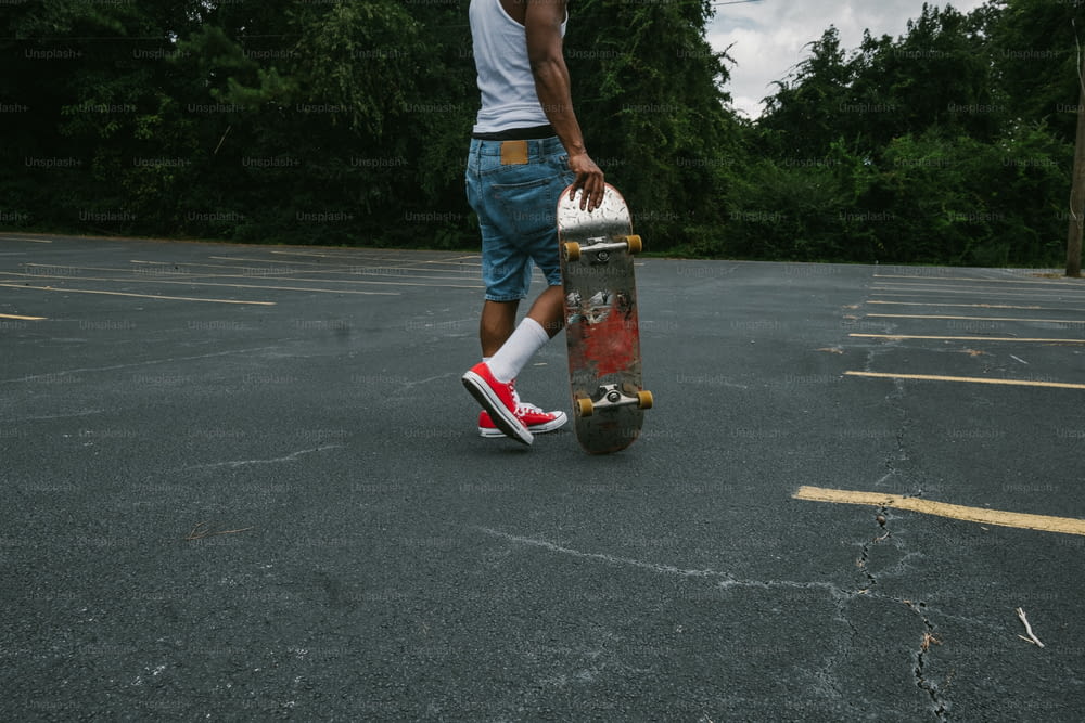 Un giovane che tiene uno skateboard in un parcheggio