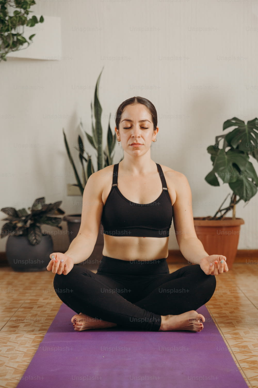 uma mulher sentada em uma posição de ioga com os olhos fechados