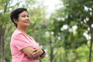 Retrato da confiante mulher adulta asiática madura com os braços cruzados em um parque ao ar livre.