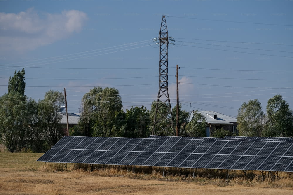 a row of solar panels in a field with power lines in the background