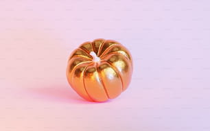 a gold pumpkin sitting on top of a pink surface