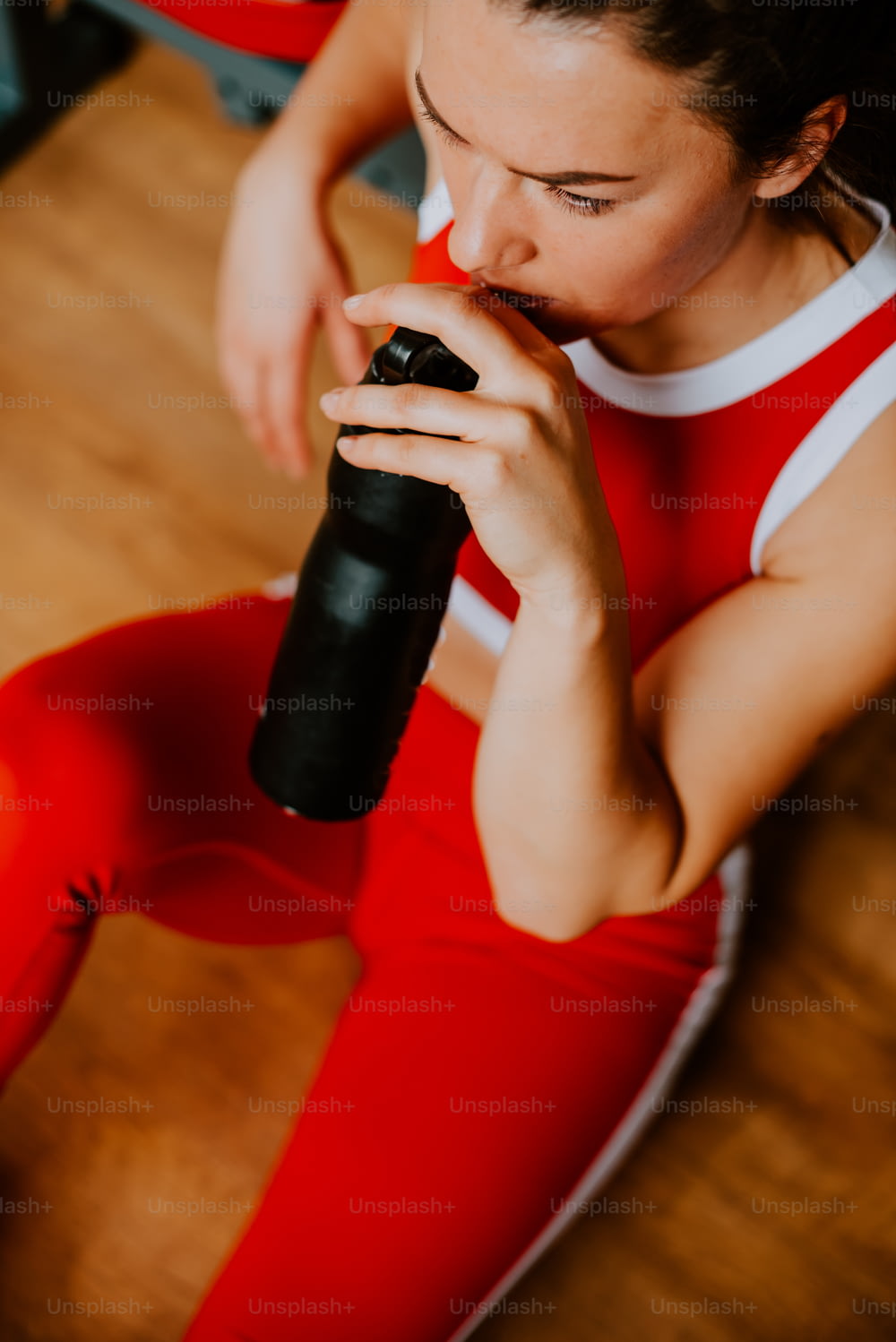 una donna seduta sul pavimento che beve da una bottiglia