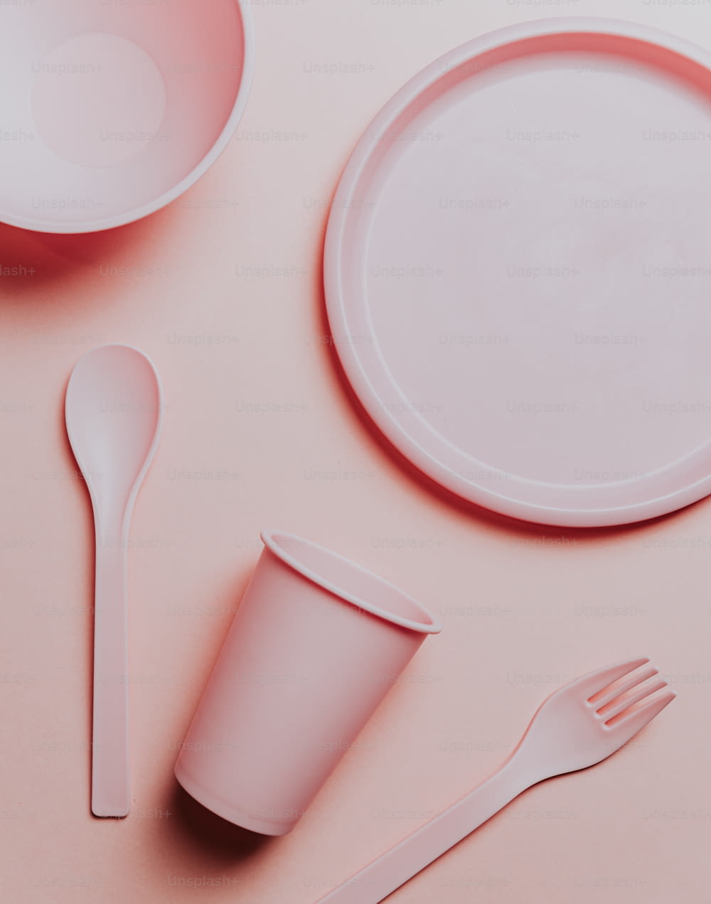 a pink table setting with a plate, fork, and cup