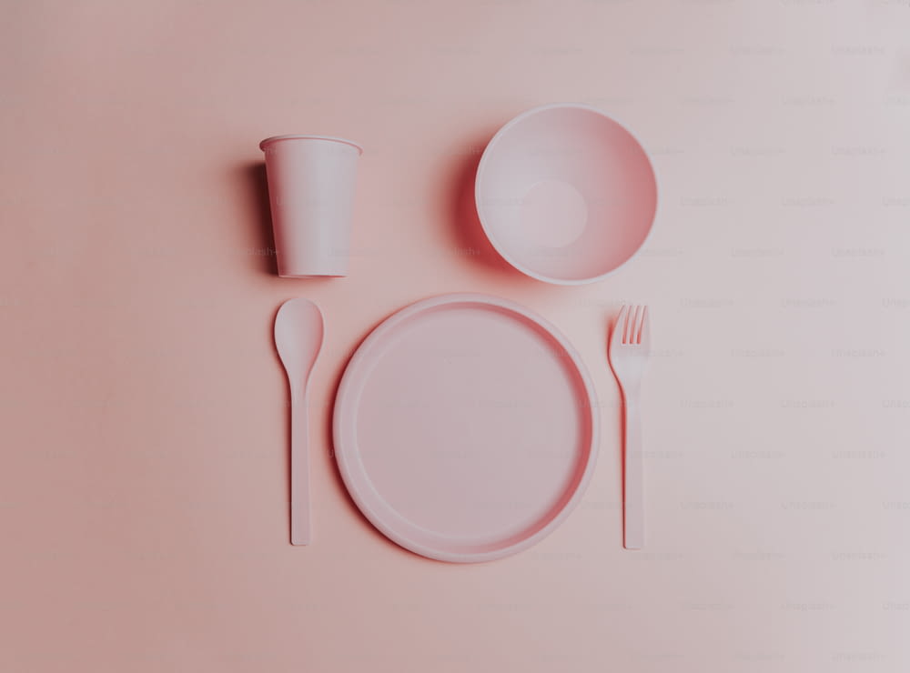 um cenário de mesa rosa com um prato, garfo e copo