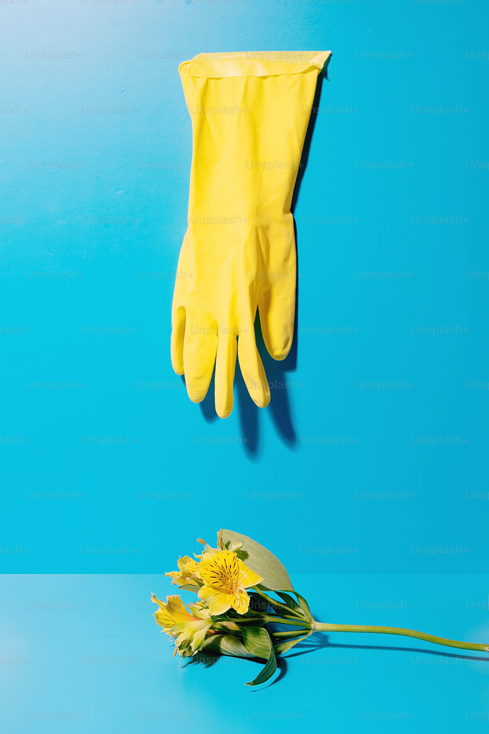 ein gelber Handschuh und gelbe Blumen auf blauem Hintergrund