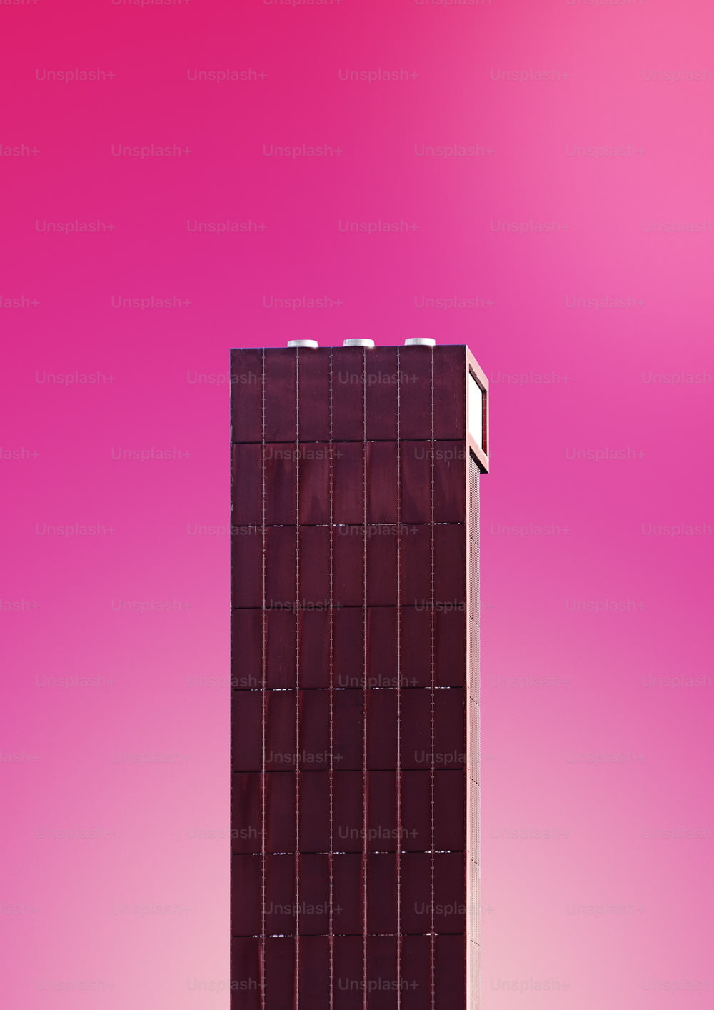 Un edificio alto de color marrón con un fondo rosa