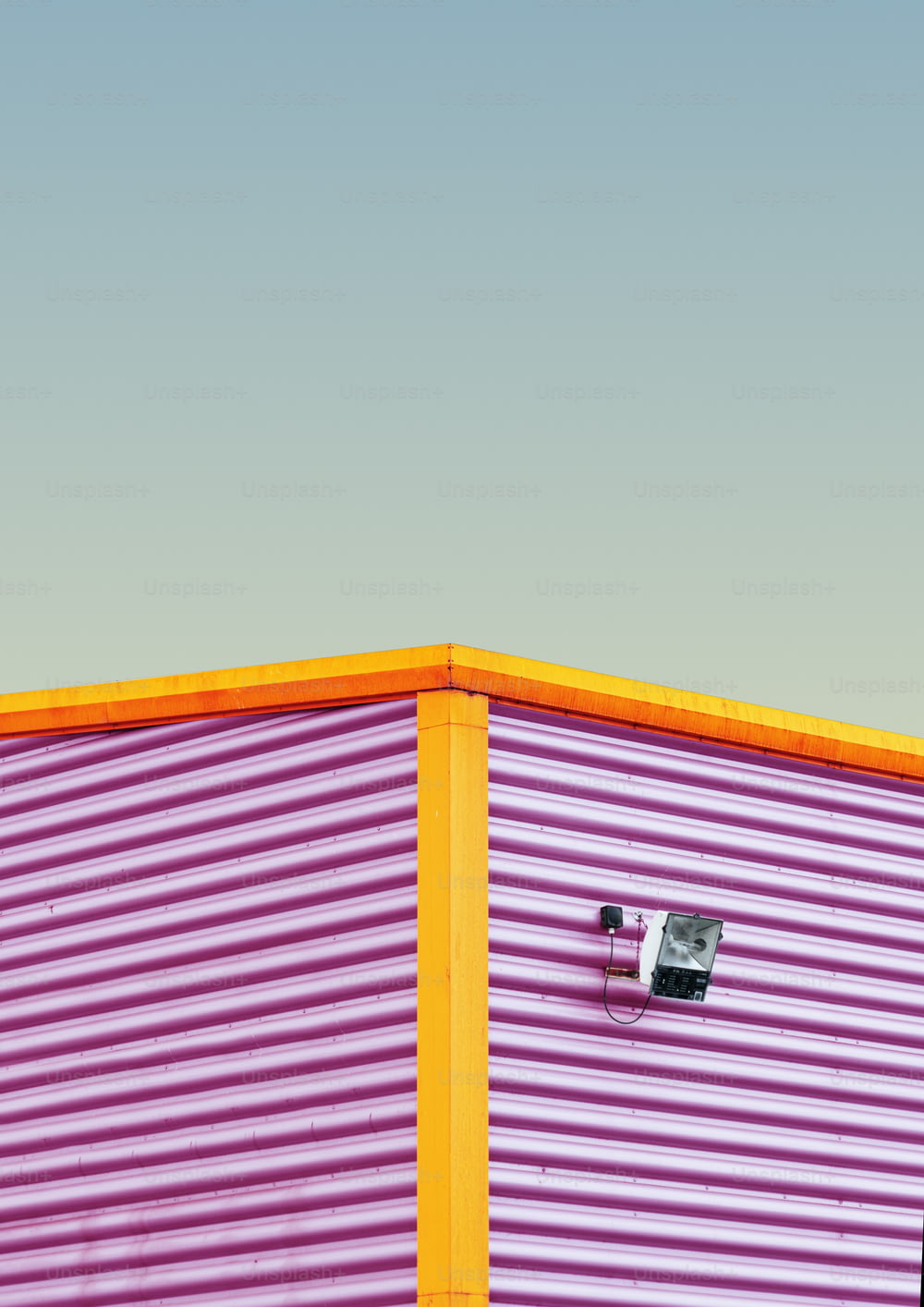 a pink and yellow building with a camera attached to it