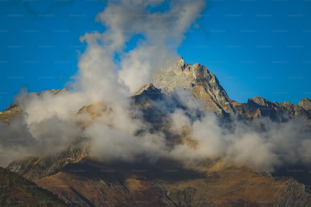 Ein in Wolken gehüllter Berg mit einem blauen Himmel im Hintergrund