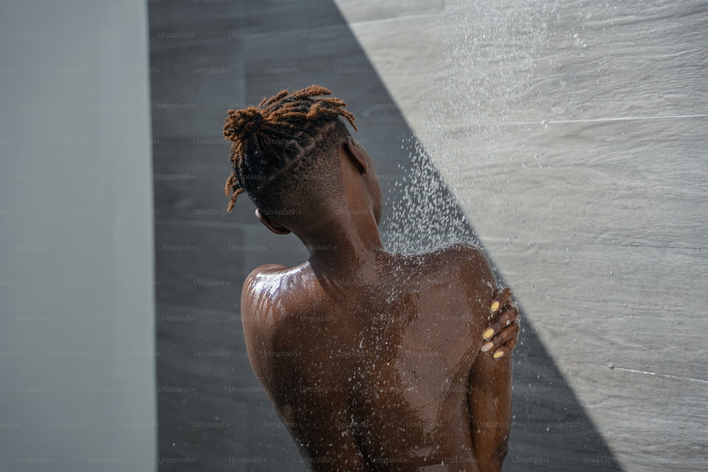 Una donna con i dreadlocks in piedi in una doccia