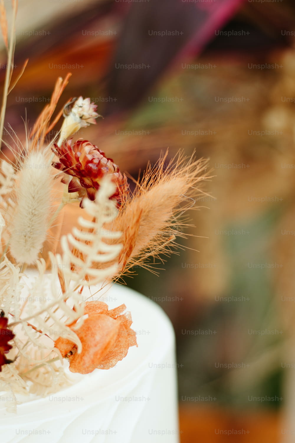 a close up of a cake decorated with dried flowers