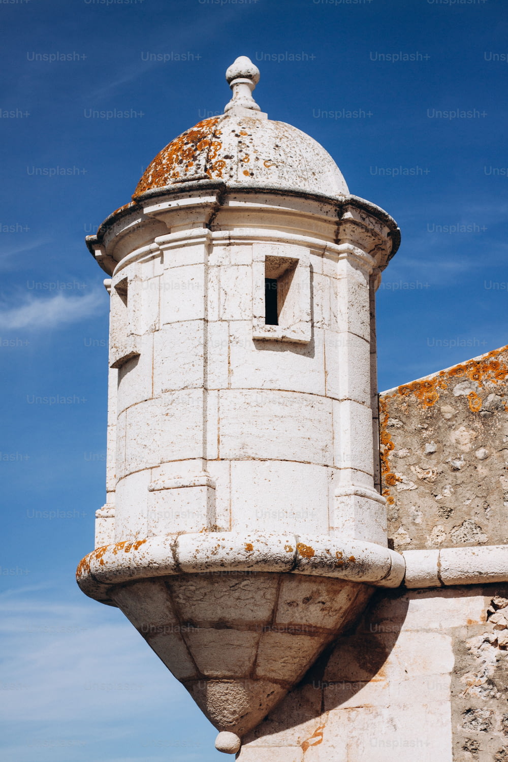 Una torre blanca con un techo oxidado contra un cielo azul