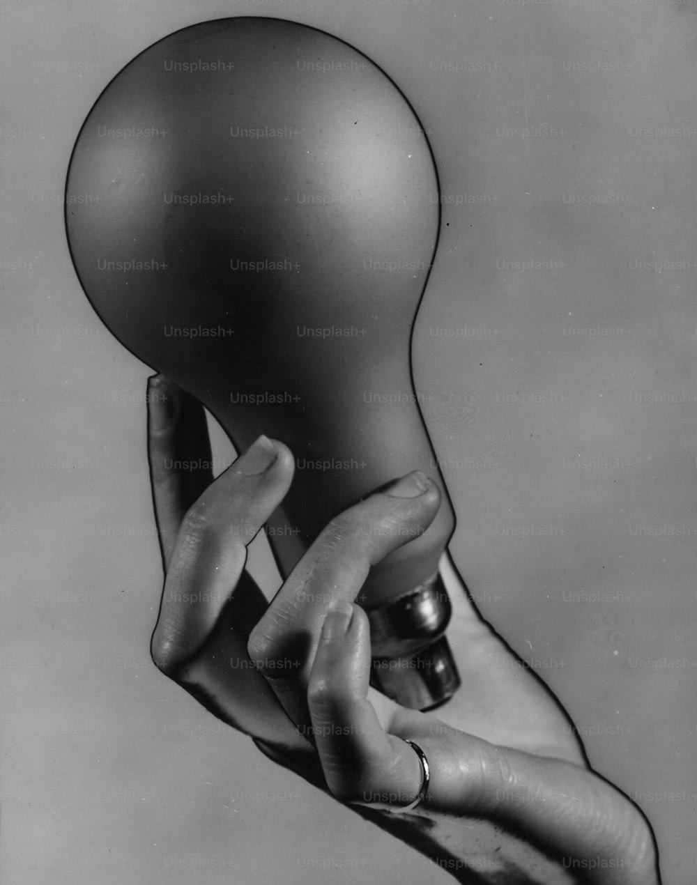 vers 1936 : Une seule main avec une bague à l’auriculaire, tenant une grosse ampoule électrique.  Image solarisée.  (Photo de Chaloner Woods/Getty Images)